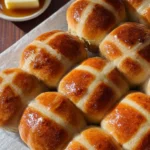Classic Hot Cross Buns 2 classic hot cross buns golden and glossy with butter on the side