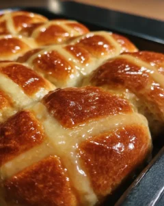 soft hot cross buns baked until glossy and golden in a dark pan