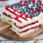 American Flag Cake layered with cream filling and topped with blueberries and raspberries in a patriotic design