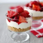 berry yogurt cheesecakes served in glass dessert cups with fresh strawberries and creamy cheesecake layers