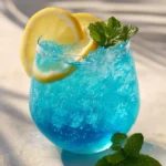 blue drink mocktail with citrus slices and ice in a clear glass