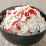 Creamy Cheesecake Salad Recipe with fresh strawberries and crunchy topping in a black serving bowl