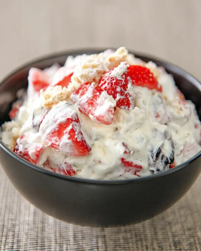Creamy Cheesecake Salad Recipe with fresh strawberries and crunchy topping in a black serving bowl