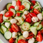 Cucumber Caprese Salad with cherry tomatoes, mozzarella pearls, and fresh cucumber slices