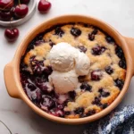 Easy Cherry Cobbler topped with vanilla ice cream and baked sweet cherries