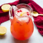 Easy Fruit Punch Beverage served in a glass pitcher with lemon slices, ice, and fresh fruit