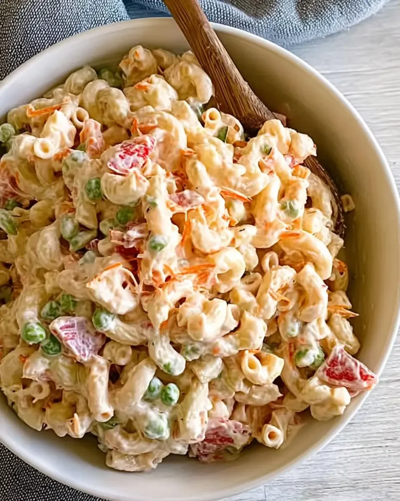 Greek Yogurt Macaroni Salad served in a bowl with peas, carrots, and creamy dressing
