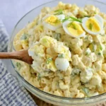 Macaroni Salad with Deviled Eggs served in a bowl with creamy dressing and fresh herbs