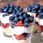 Mini Trifles with Mixed Berries layered with cake, whipped cream, strawberries, and blueberries
