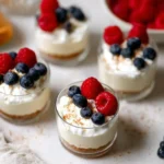 No-Bake Cheesecake Cups topped with raspberries and blueberries in mini dessert glasses