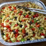 Pasta Salad for a Crowd with rotini pasta, cherry tomatoes, olives, cucumbers, and cheese