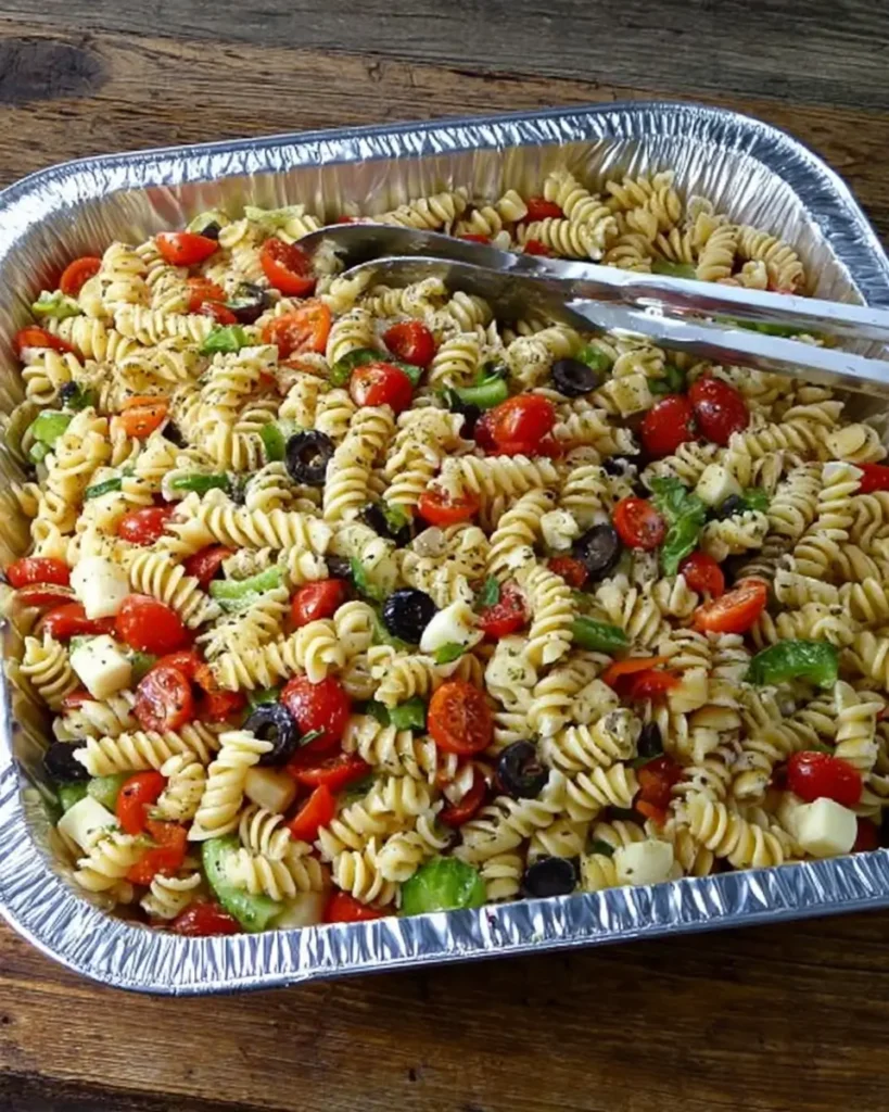 Pasta Salad for a Crowd with rotini pasta, cherry tomatoes, olives, cucumbers, and cheese