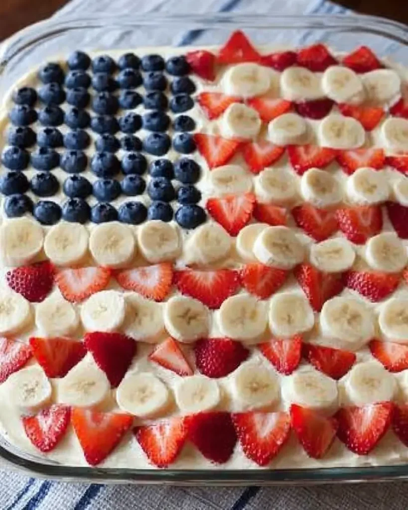 Patriotic Fruit Pizza decorated with strawberries, blueberries, and bananas in an American flag design