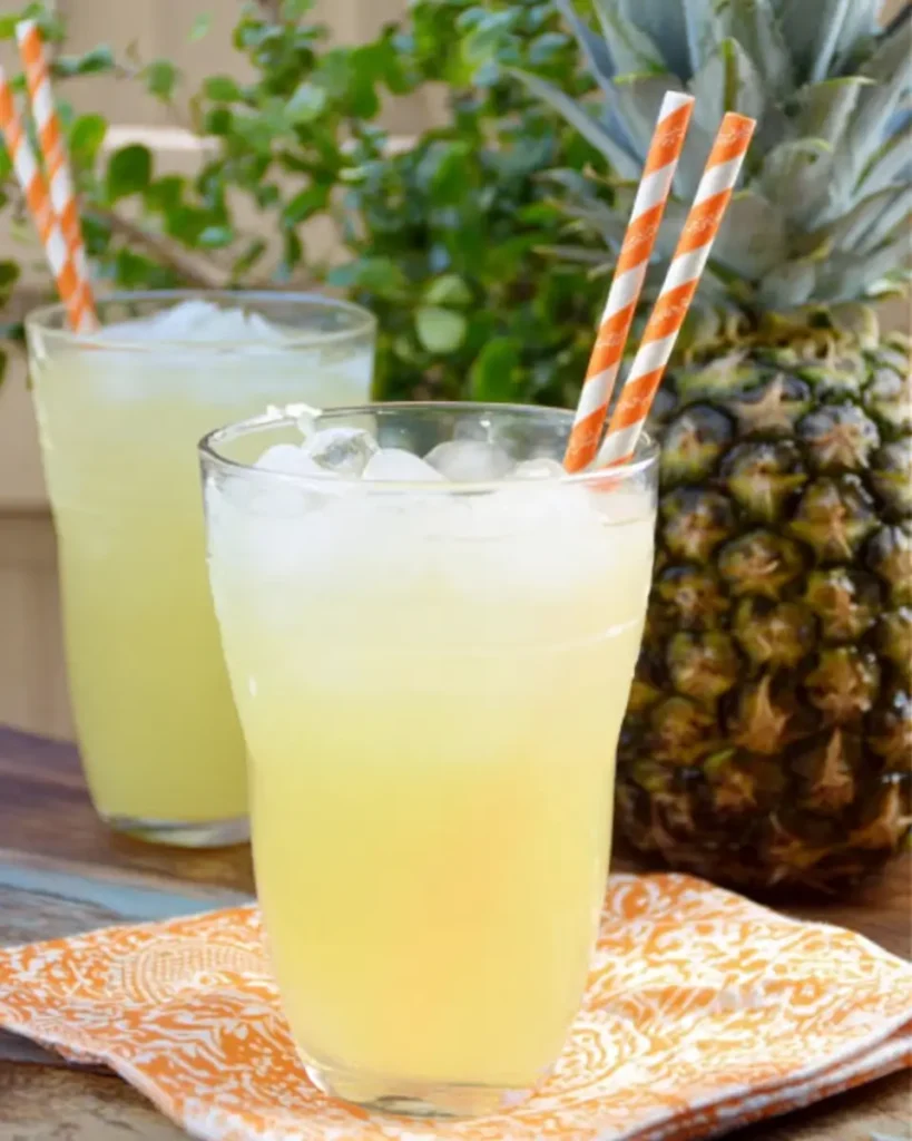 Pineapple Lemonade served over ice with fresh pineapple and striped paper straws