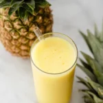 Pineapple Lemonade smoothie served in a tall glass with fresh pineapple