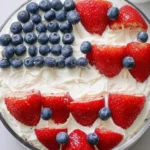 Red white blue desserts topped with strawberries and blueberries arranged in an American flag design