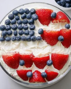 Red white blue desserts topped with strawberries and blueberries arranged in an American flag design