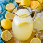 Refreshing Summer Classic Homemade Lemonade Recipe served in a glass pitcher with fresh lemons and ice